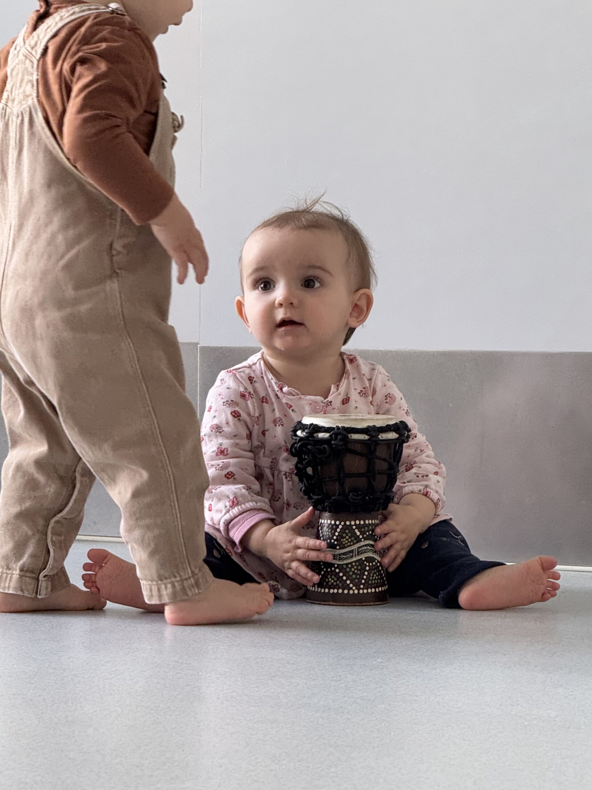 Bébé en crèche découvrant un tambour pendant un atelier d’éveil musical