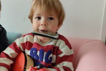 Enfant en crèche jouant du tambour et de l’harmonica pendant un atelier d’éveil musical