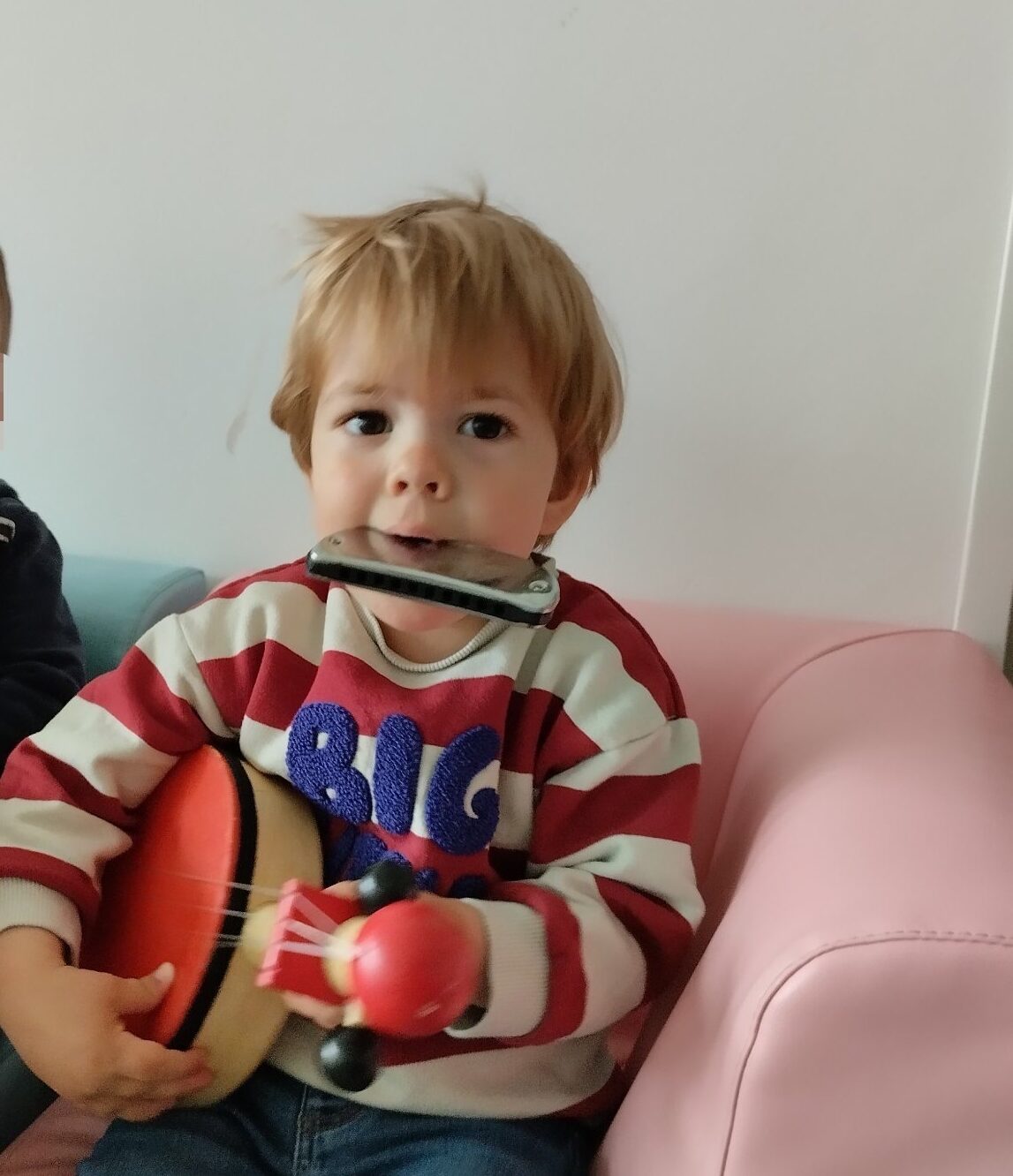 Enfant en crèche jouant du tambour et de l’harmonica pendant un atelier d’éveil musical