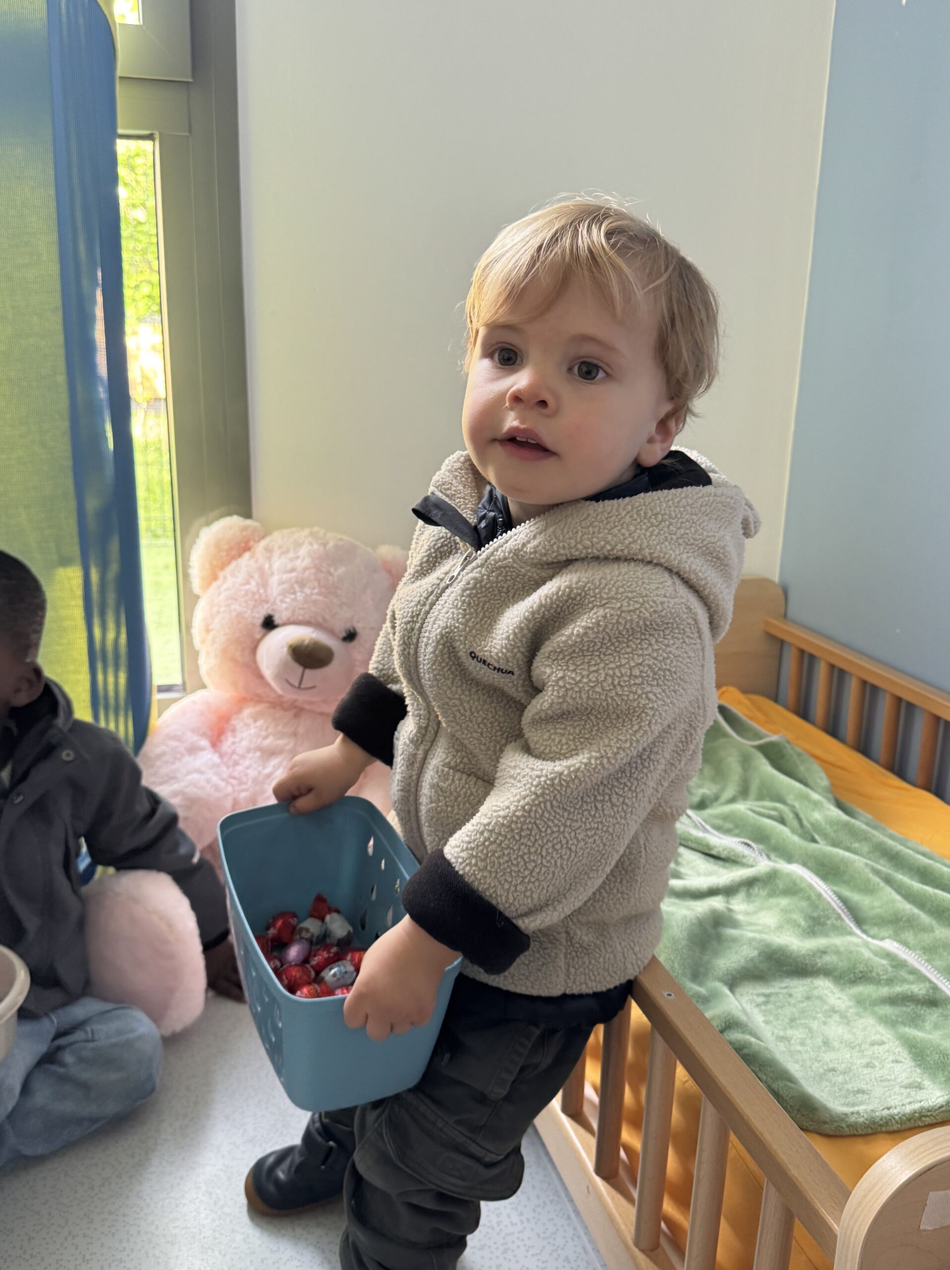 Un jeune enfant tient un panier rempli de chocolats après une chasse aux oeufs à la crèche Les Libellules à Vannes