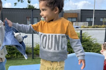 Deux enfants en crèche tenant un doudou, moment de transition rassurant en extérieur