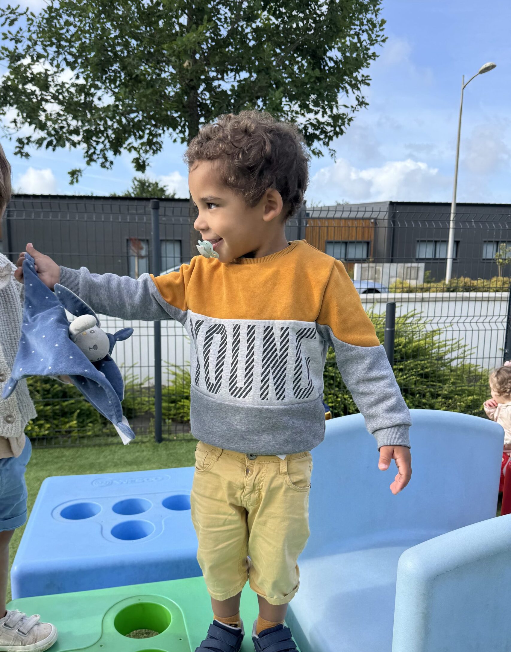 Deux enfants en crèche tenant un doudou, moment de transition rassurant en extérieur