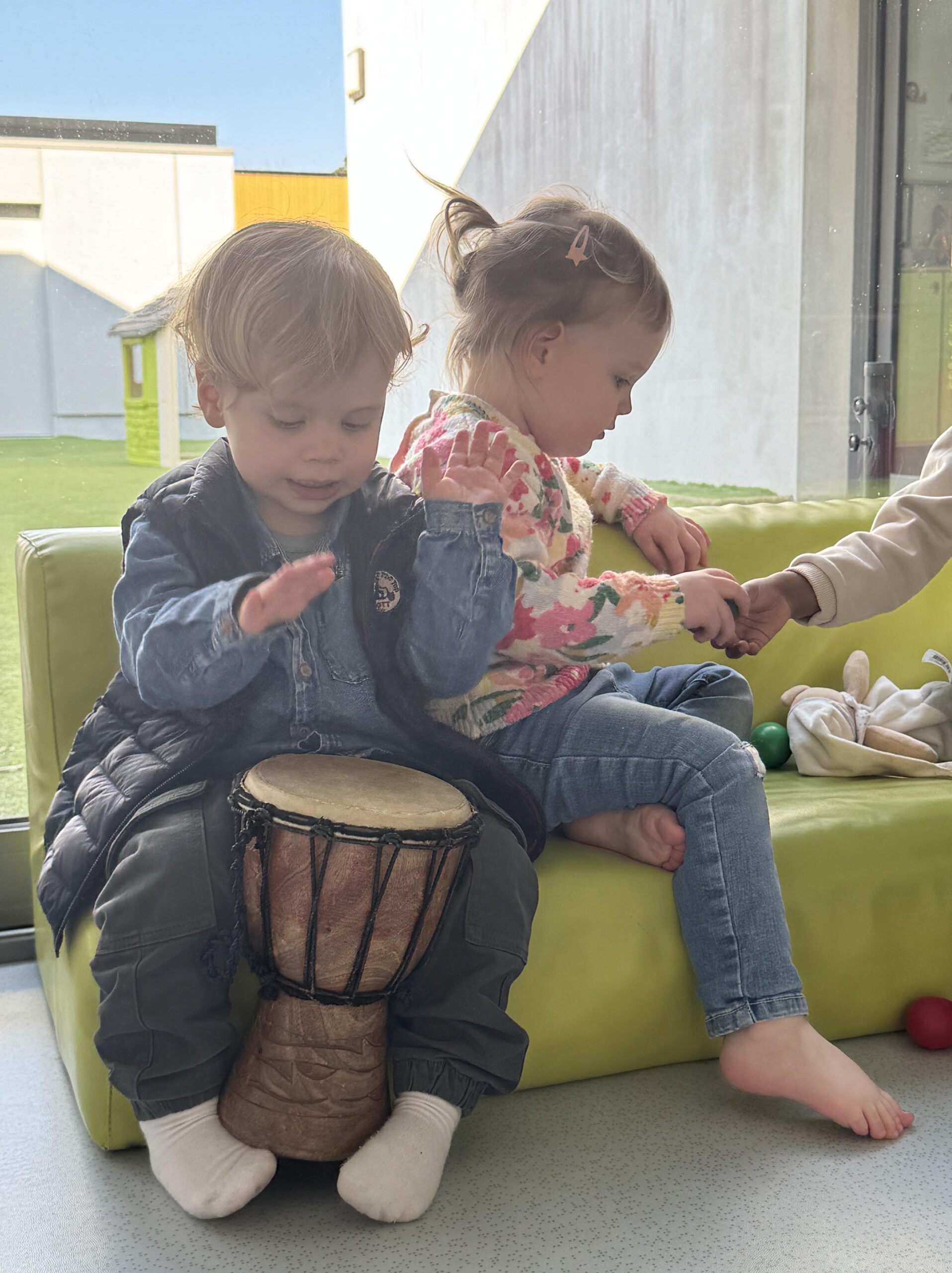 Enfant assis jouant du djembé lors d’un atelier musical à la crèche