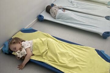 Un enfant dort paisiblement sur un lit bleu pendant la sieste à la crèche