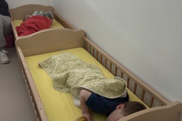 Deux enfants dorment dans des lits en bois à la crèche, chacun enveloppé dans une couverture