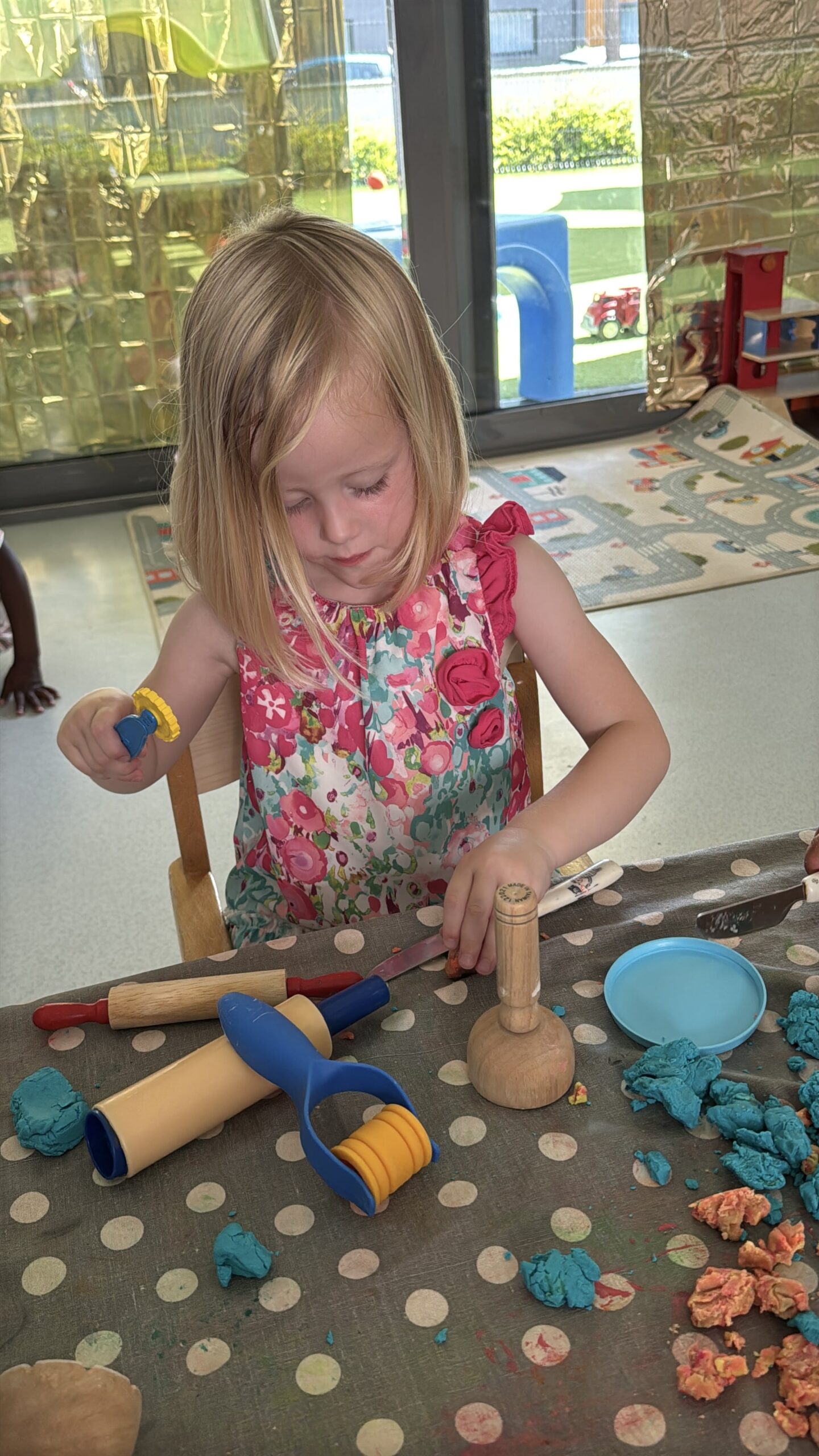 Petite fille concentrée à la crèche Les Libellules à Vannes, en train de manipuler de la pâte à modeler avec des outils à la crèche