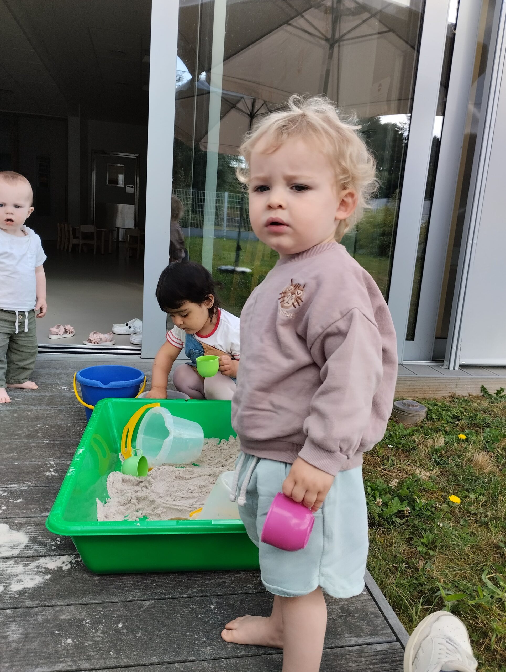 Enfant jouant au sable en extérieur à la crèche Les Papillons de Pontivy, favorisant la motricité fine et l'autonomie