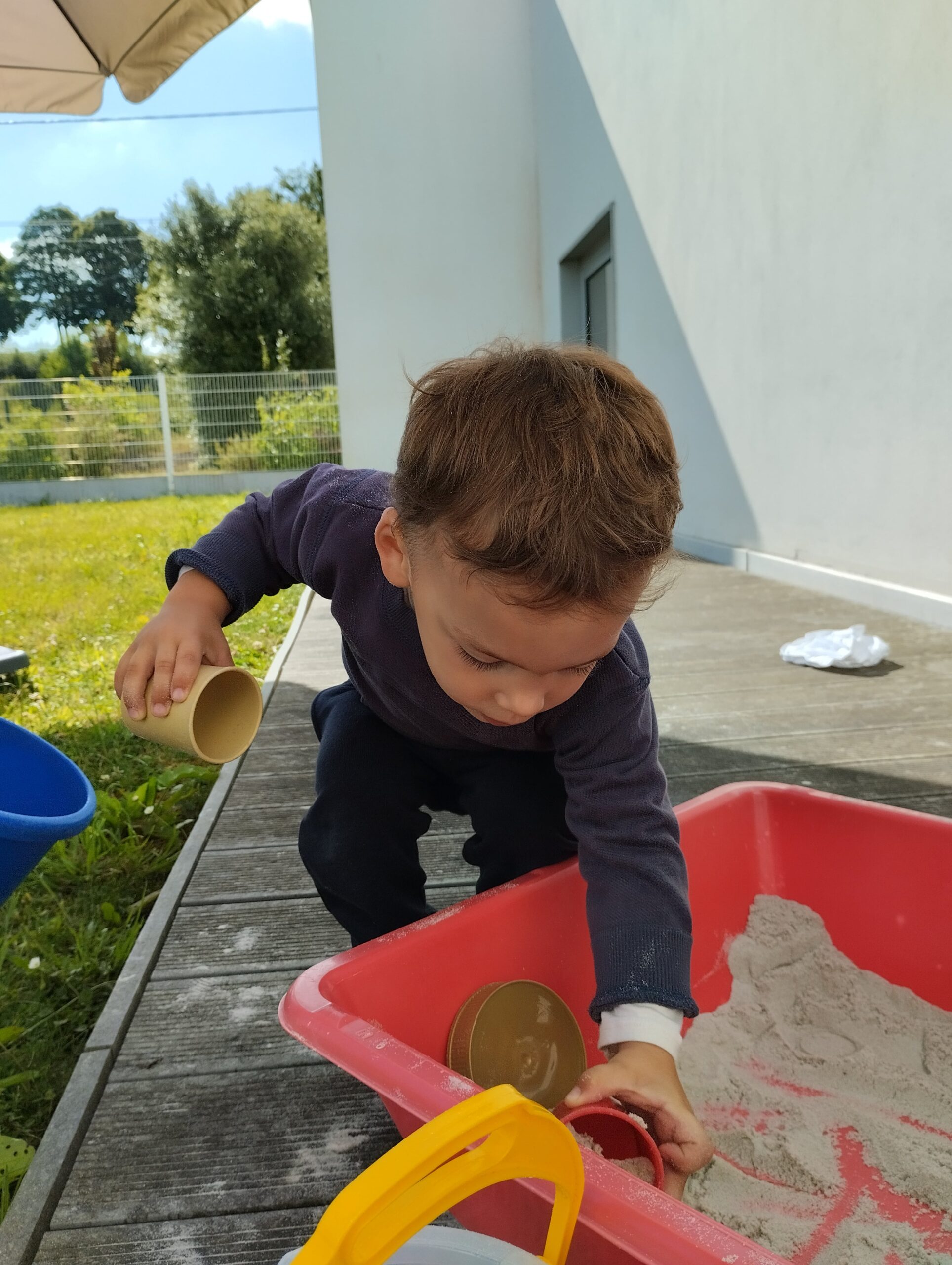 Enfant jouant au sable à la crèche Les Papillons de Pontivy, en extérieur, ce qui favorise la motricité fine et l'autonomie