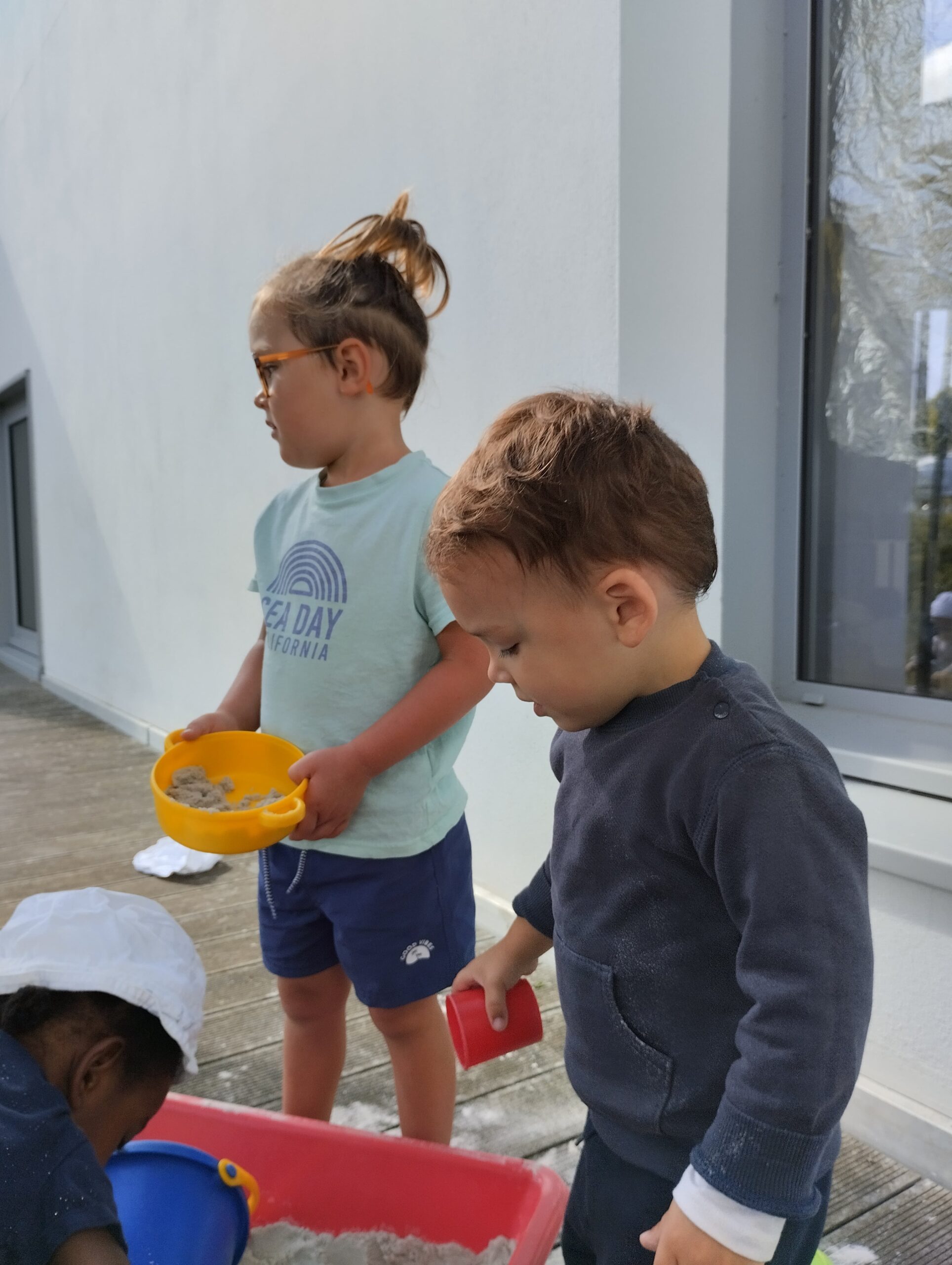 Trois enfants jouant ensemble dans un bac à sable à la crèche Les Papillons de Pontivy.
