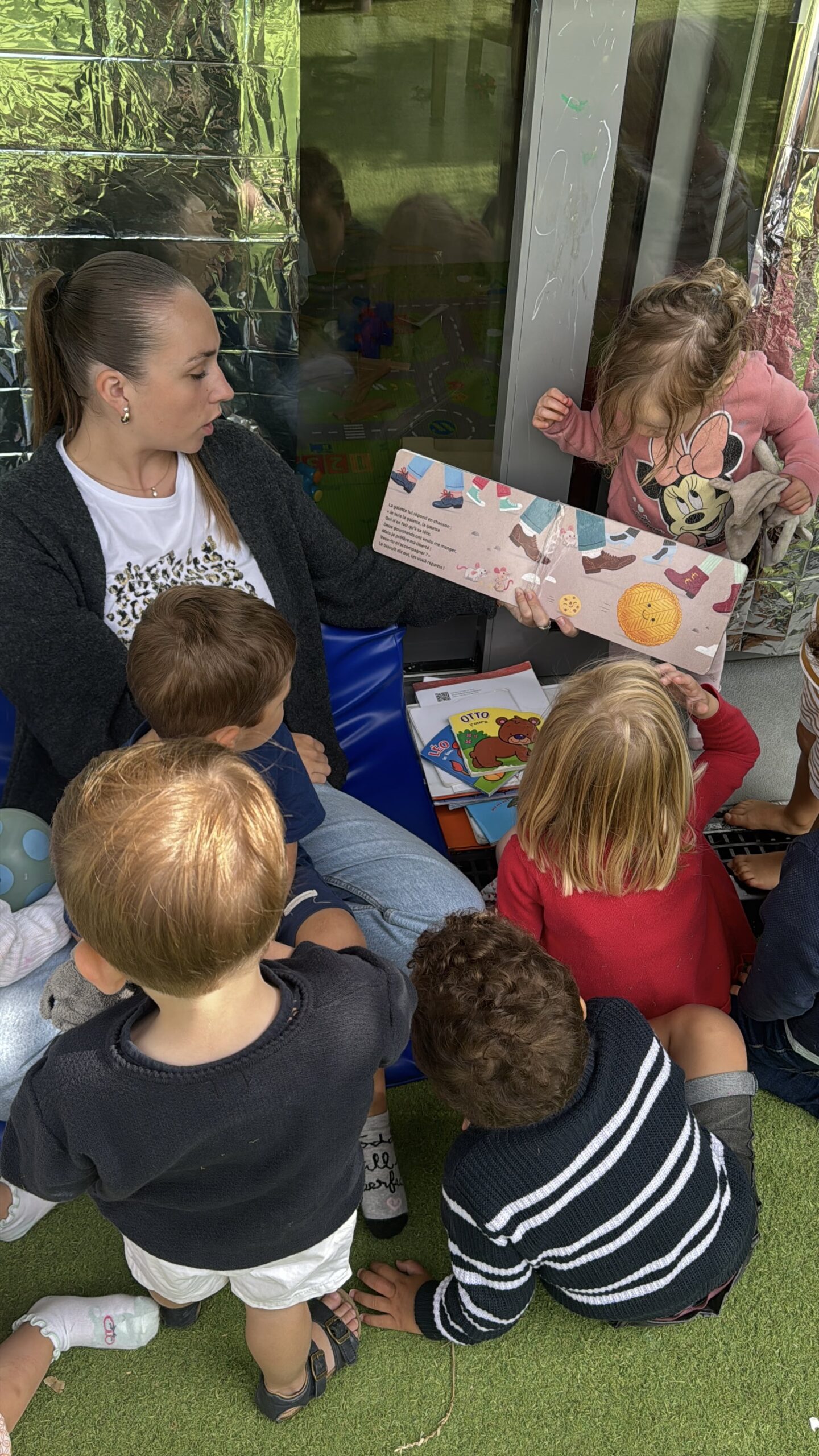 Une professionnelle lit un livre à un groupe d'enfants assis autour d'elle à la crèche Les Libellules à Vannes.
