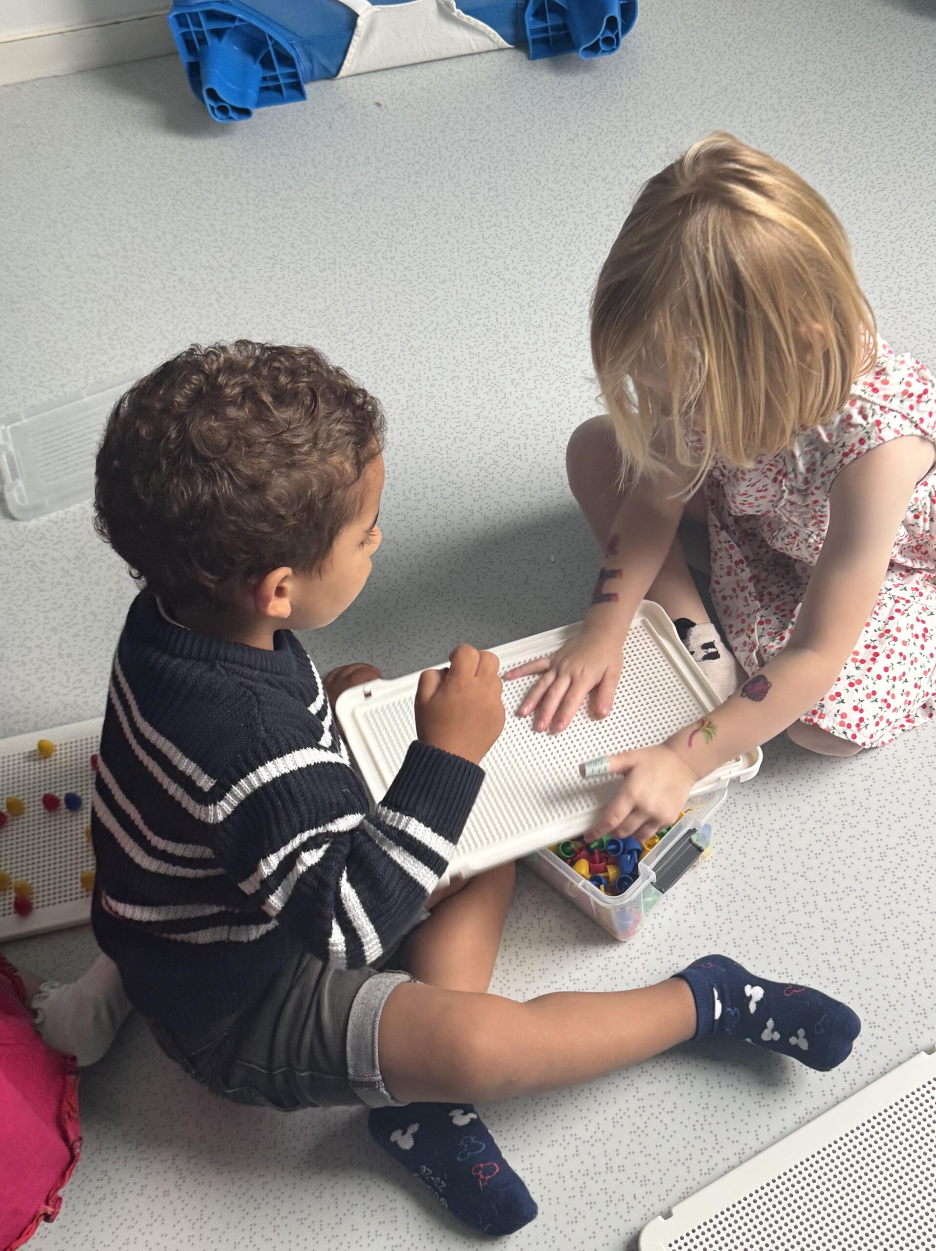 Deux enfant coopèrent autour d'un jeu de picot sur le sol de la crèche Les Libellules à Vannes