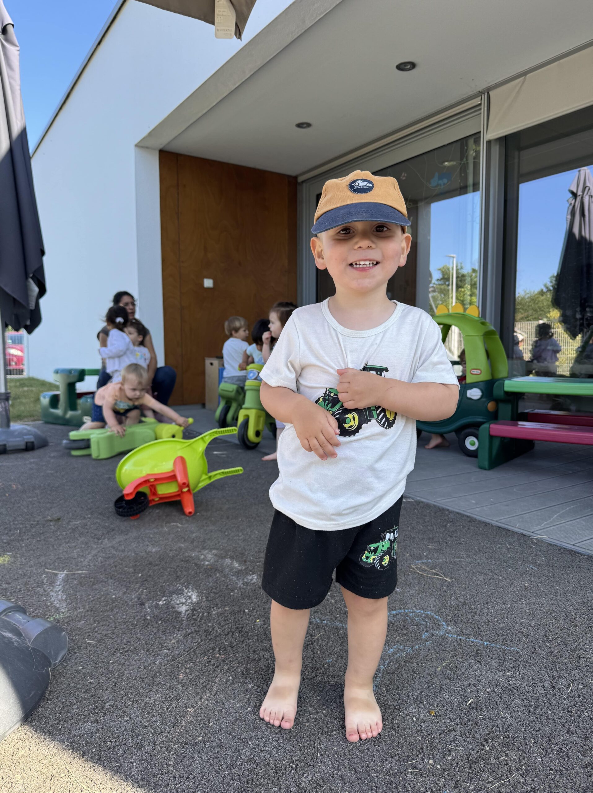Enfant en casquette souriant debout devant la crèche Les Papillons