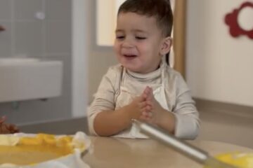 Enfant en tablier participant à un atelier cuisine d’Halloween à la crèche Les Papillons de Noyal-Pontivy, préparant un gâteau à la citrouille.