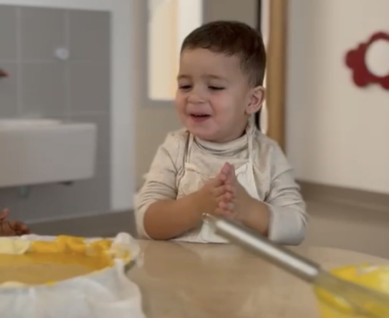 Enfant en tablier participant à un atelier cuisine d’Halloween à la crèche Les Papillons de Noyal-Pontivy, préparant un gâteau à la citrouille.